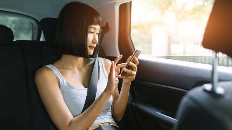 Image of a woman sitting in a car using a cell phone.