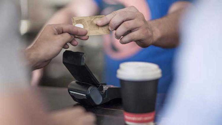 Someone hands over a credit card as a payment for coffee