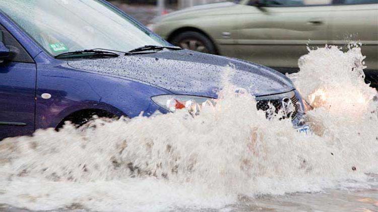 汽车行驶在被水淹没的街道上，可能会受到洪水的破坏.